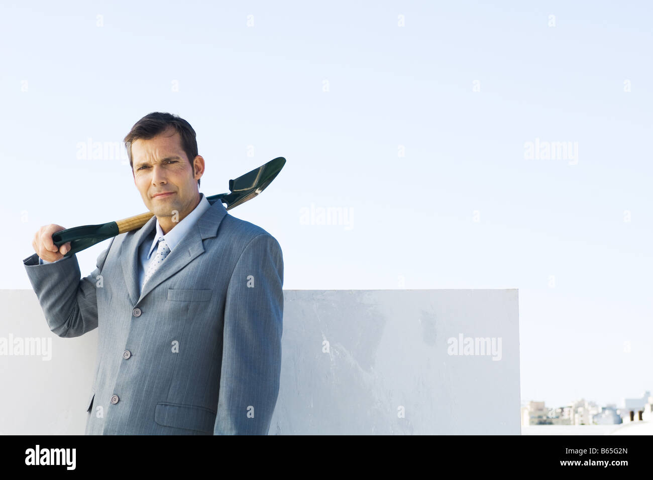 Man in suit holding shovel, looking at camera Stock Photo