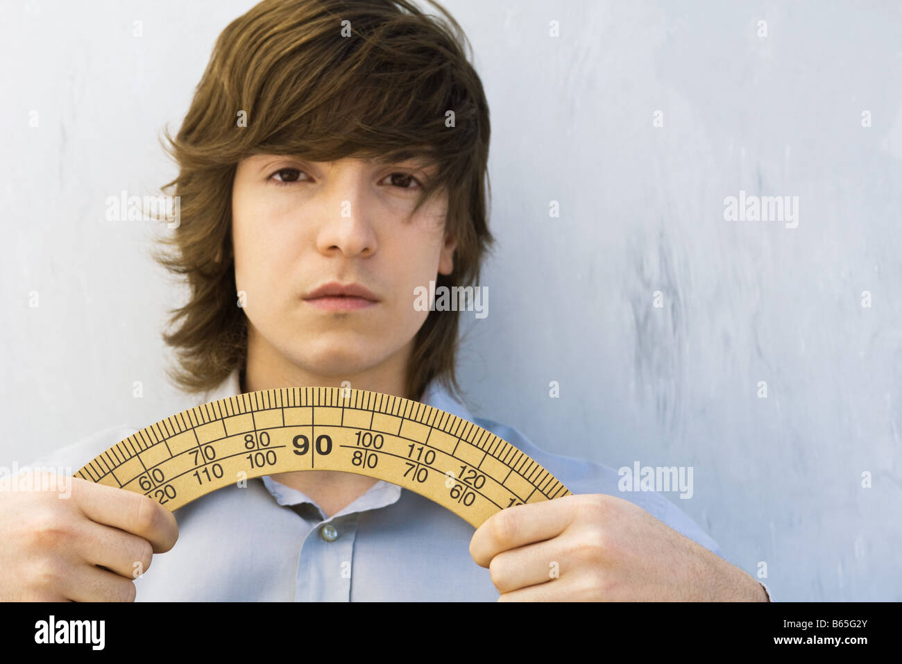 Young man holding protractor in both hands, looking at camera Stock