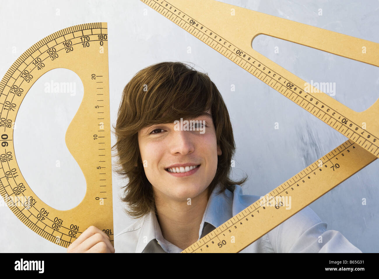 Young man holding various measuring instruments, smiling at camera Stock Photo