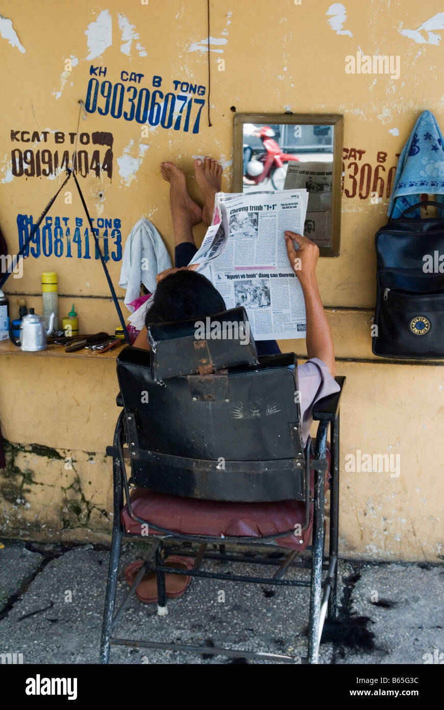 Vietnamese street barber relaxing in his chair Stock Photo