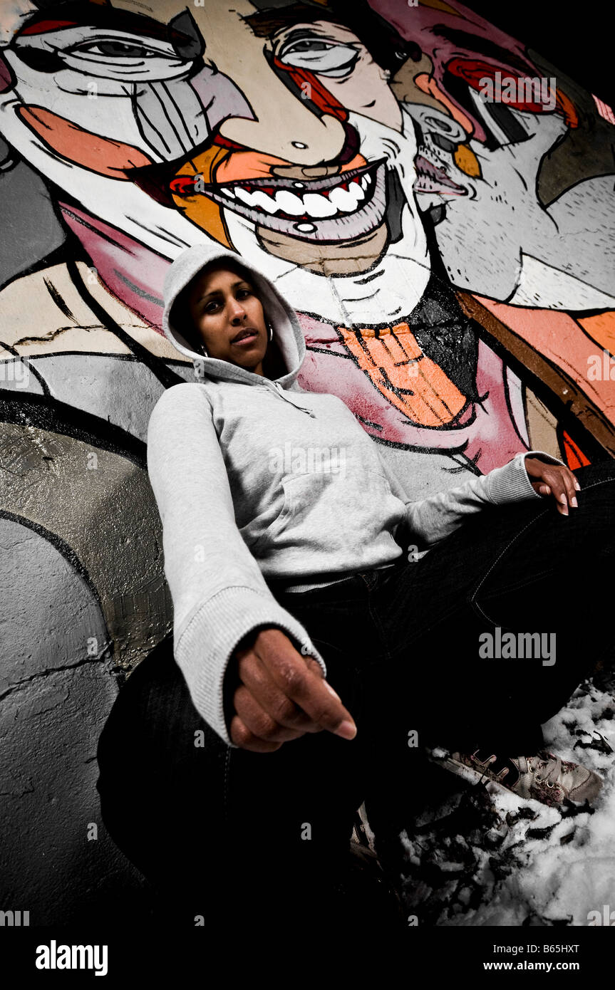 Black woman wearing a hoodie i front of a urban graffiti wall Stock Photo
