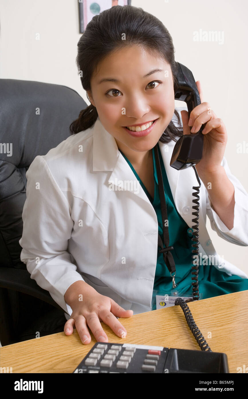 Female doctor in her office answering her phone. Stock Photo
