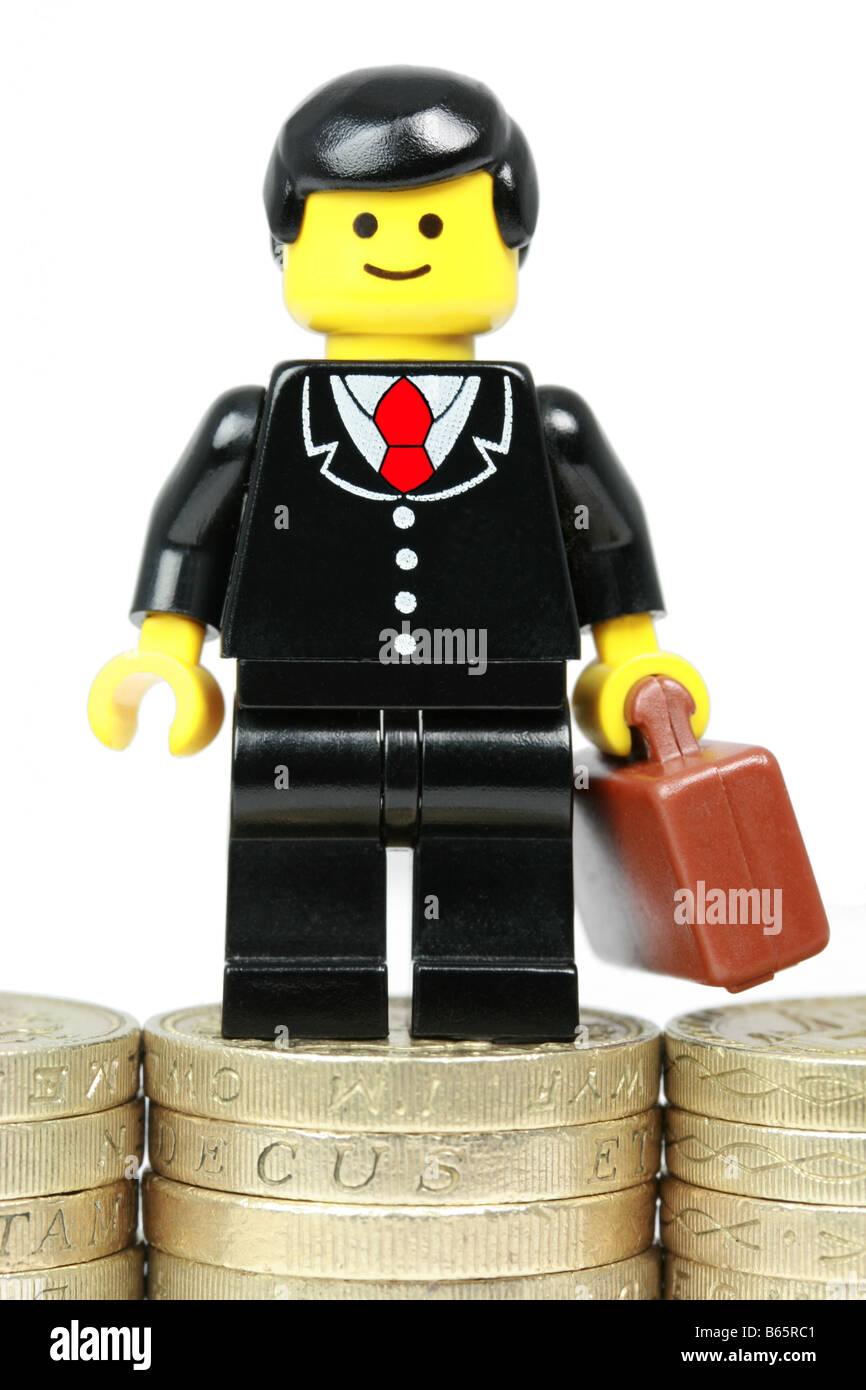 Lego businessman standing on piles of money - business success concept Stock Photo