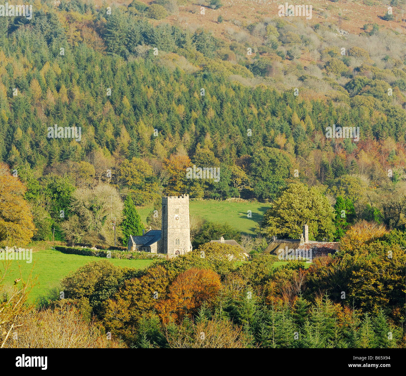 St Peters church at Buckland in the Moor below Buckland Beacon on Dartmoor National Park and surrounded by autumnal woodland Stock Photo