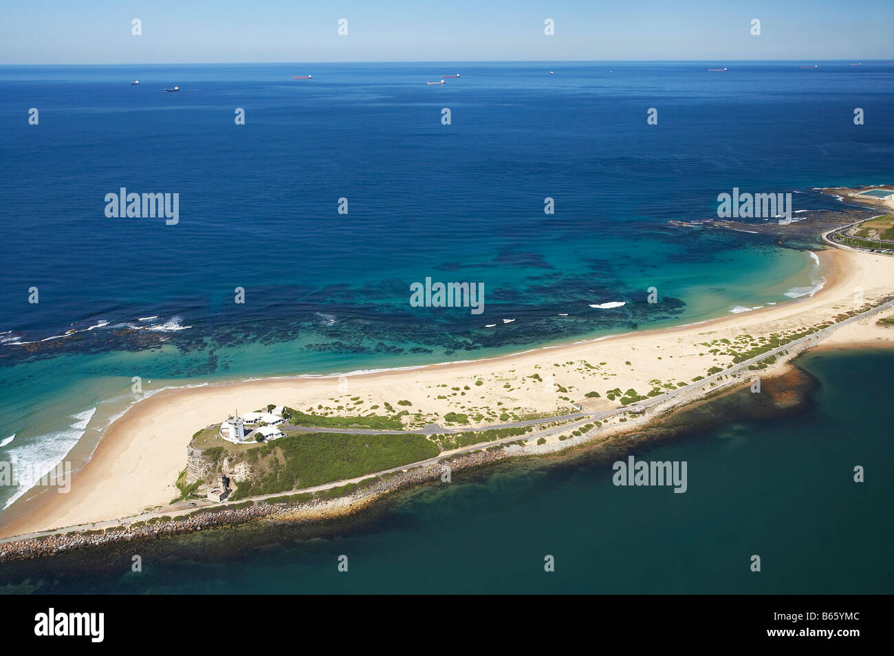 Nobbys Beach Nobbys Head and Bulk Coal Ships Waiting Offshore for Space in Port Newcastle New South Wales Australia aerial Stock Photo