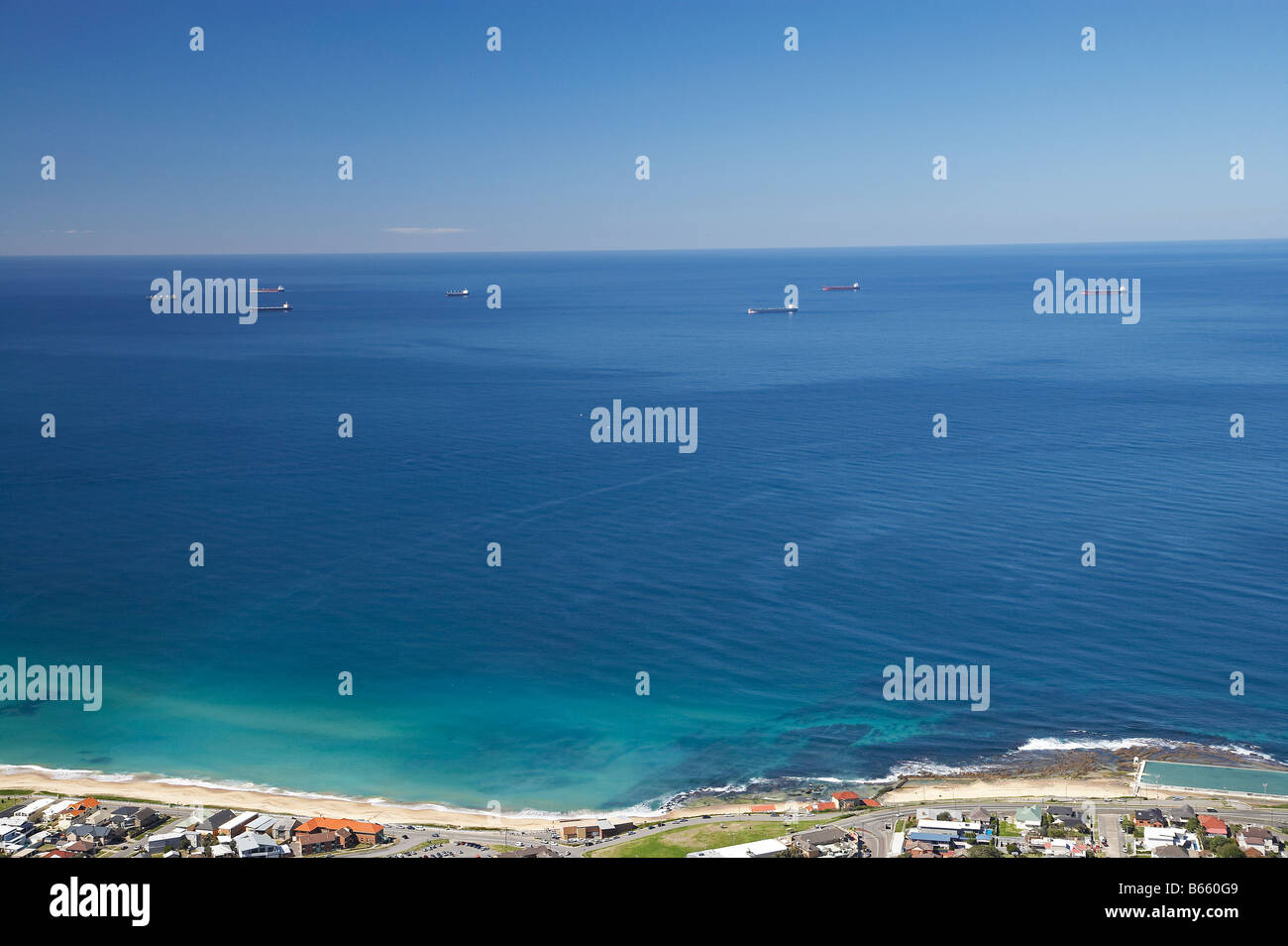 Merewether Beach and Bulk Coal Ships Waiting Offshore for Space in Port Newcastle New South Wales Australia aerial Stock Photo