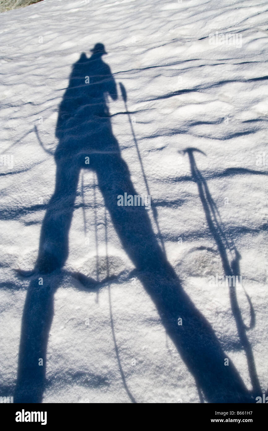 Shadow of mountain climber on snow with climbing gear (hiking poles, ice axe, rope), Klawatti Glacier, North Cascades National Park, Washington. Stock Photo