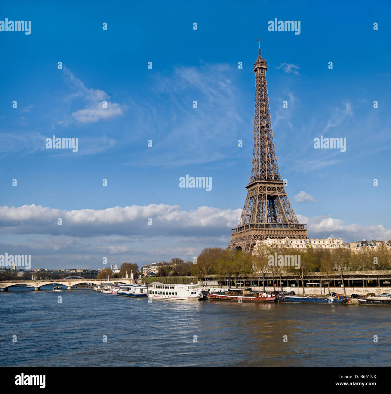 Eiffel Tower with blue skies and boats on the Seine River by Charles W. Lupica Stock Photo