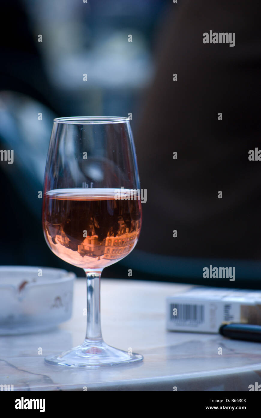 A glass of l'oeil de Perdrix reflects the city in the bottom of a wine glass Stock Photo