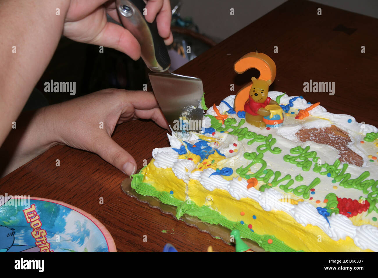 hands cutting a piece of birthday cake Stock Photo