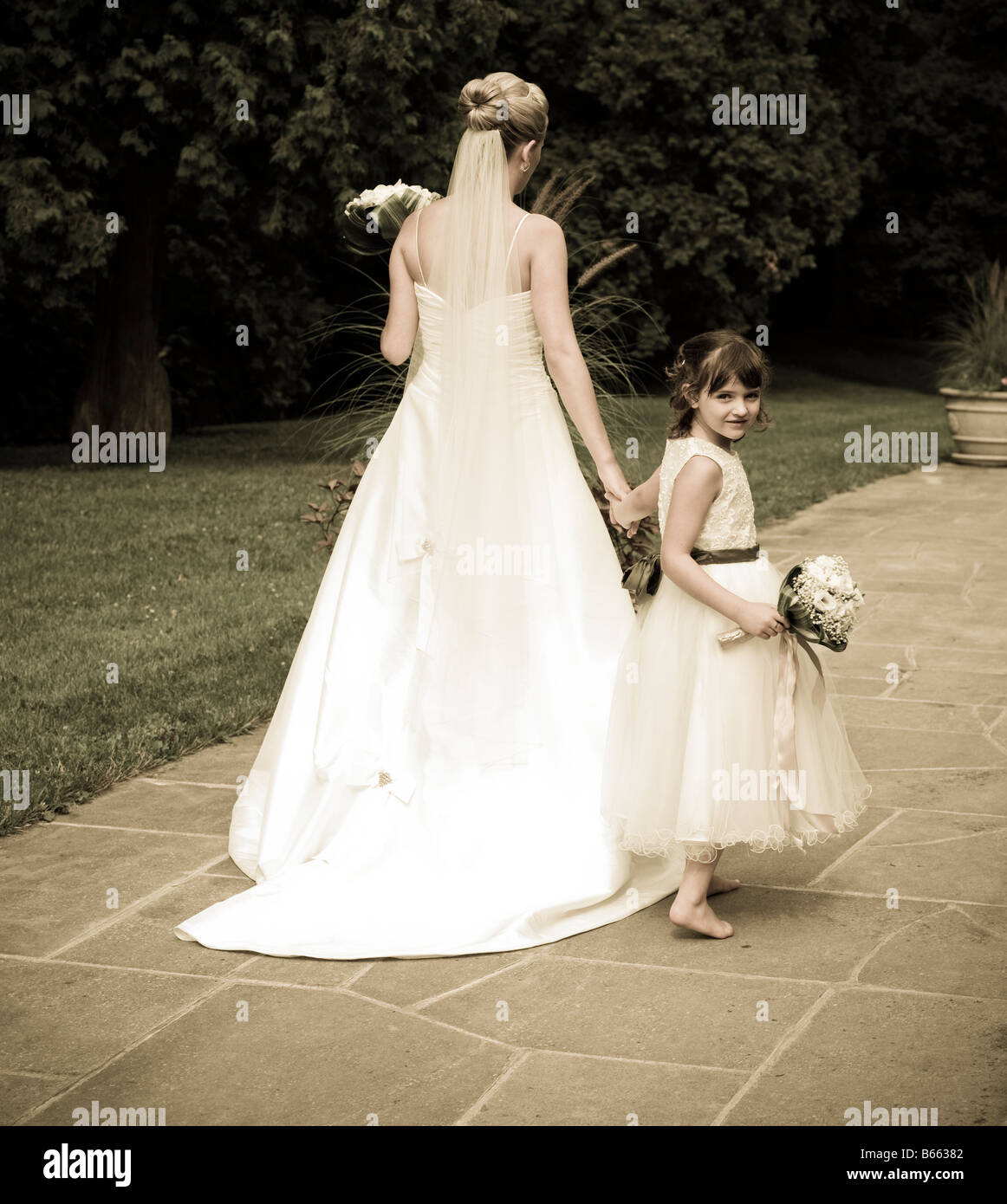bride and flower girl walking down a path Stock Photo Alamy