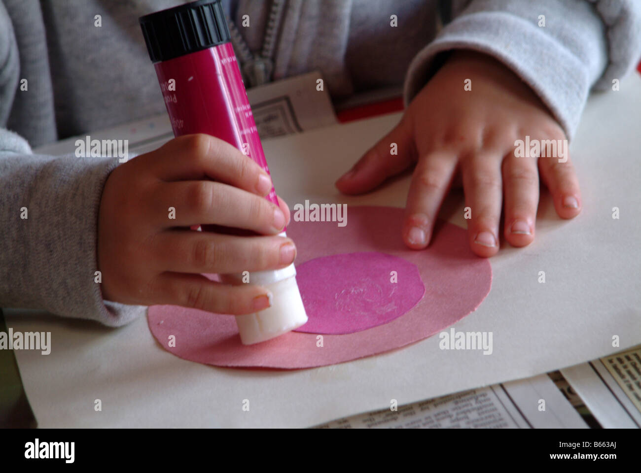 Child using a glue stick to stick shapes Stock Photo Alamy