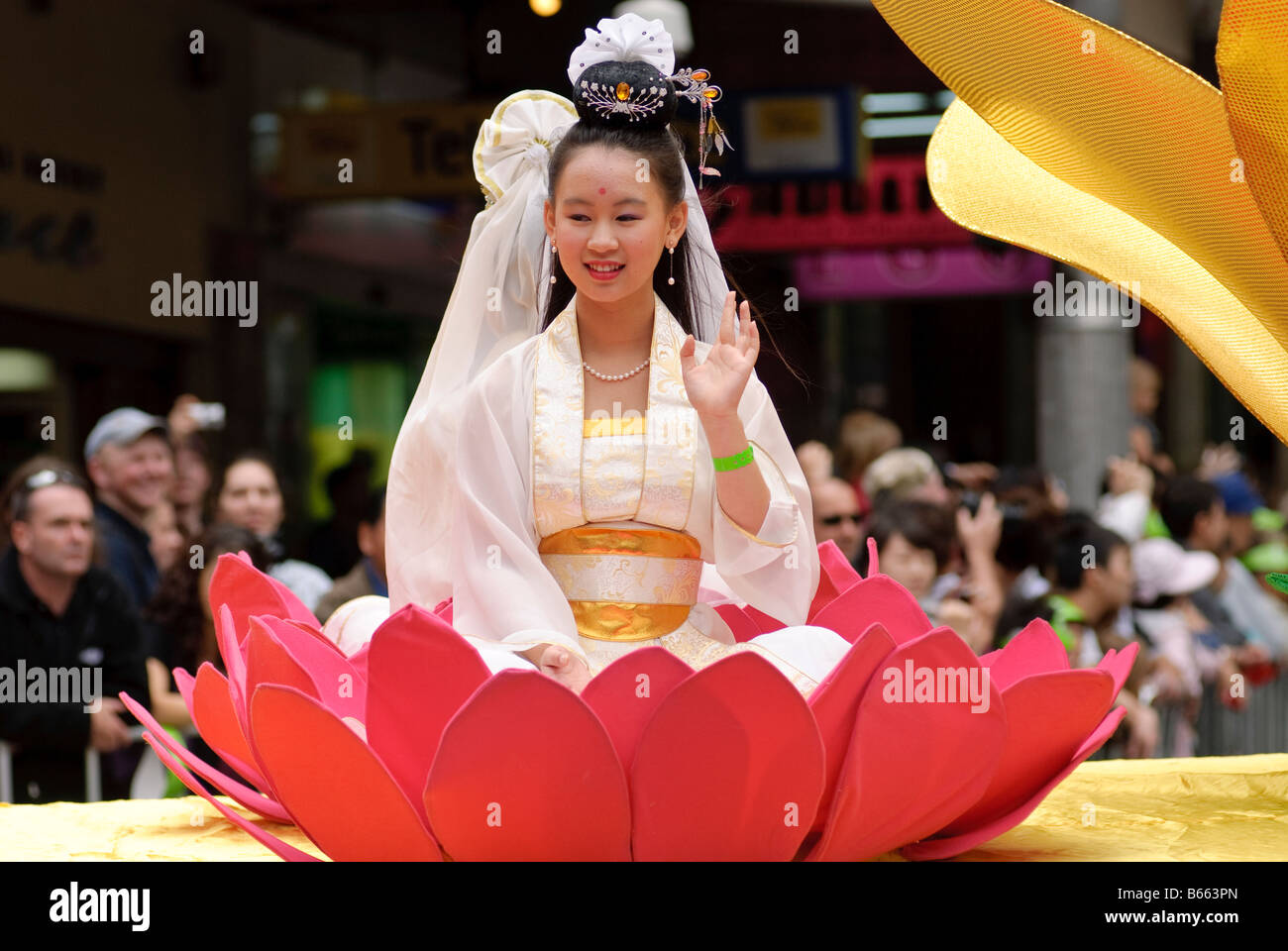 Young Chinese girl in traditional costume sitting in a lotus flower during a Chinese New Year parade. Stock Photo