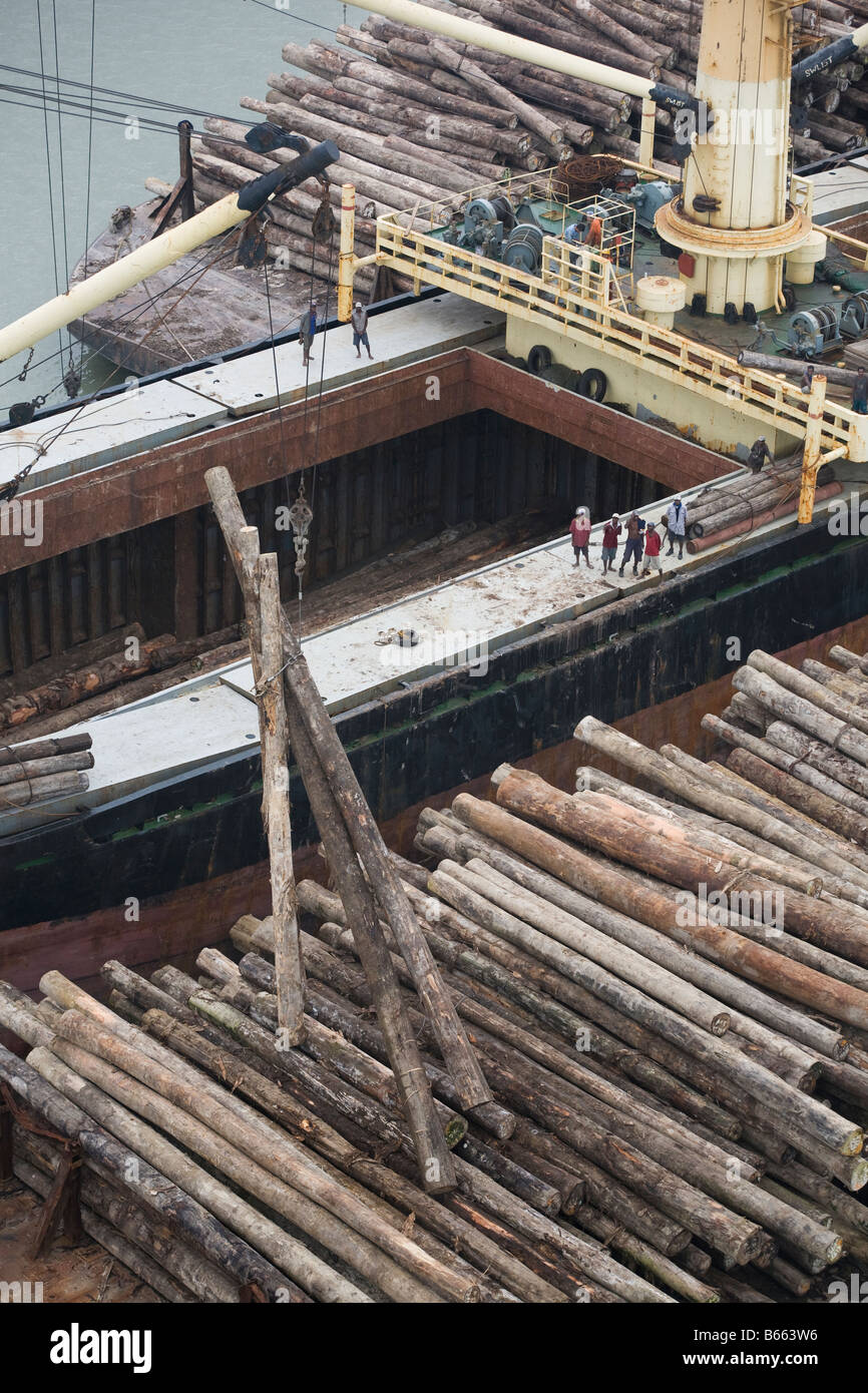 Loading of illegally cut trees from barges onto cargo ship in Paia Port, in Papua New Guinea. Stock Photo