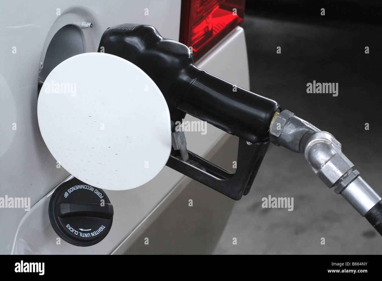 A gas pump handle in a gas tank filling up Stock Photo Alamy