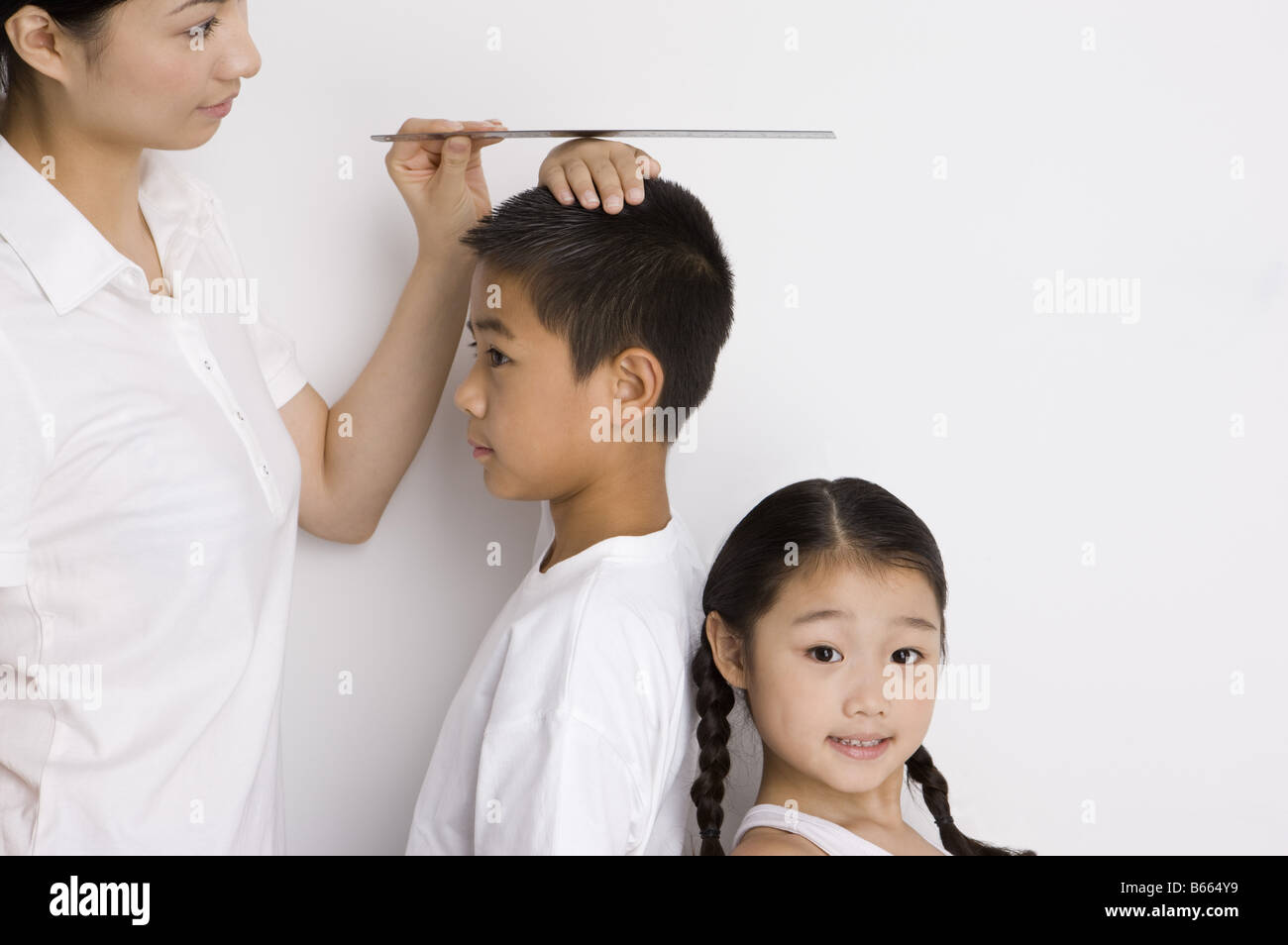 Mother measuring the height of two children Stock Photo