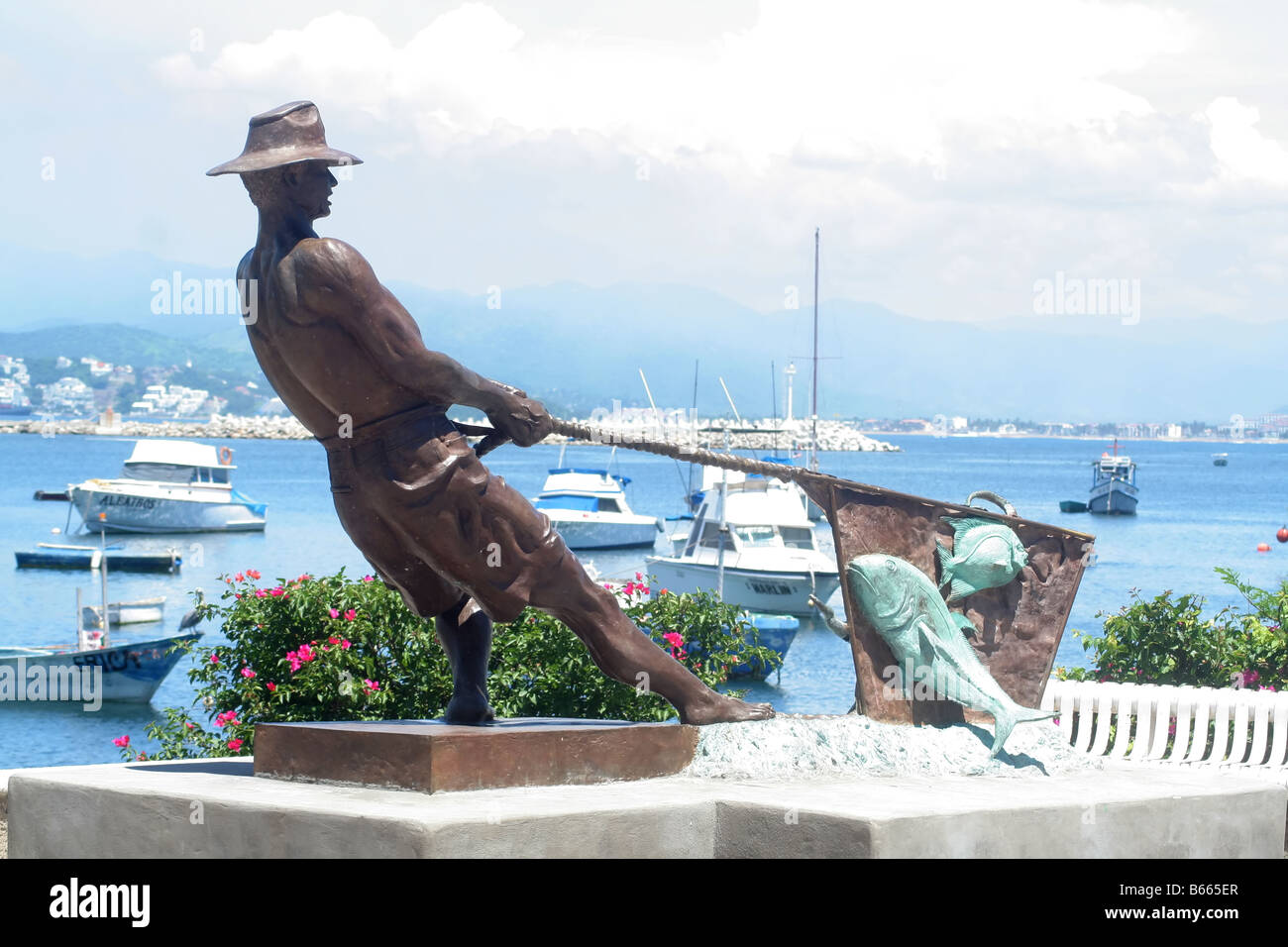 A statue of a fisherman pulling in a net of fish on a pier in Manzanillo Mexico Stock Photo