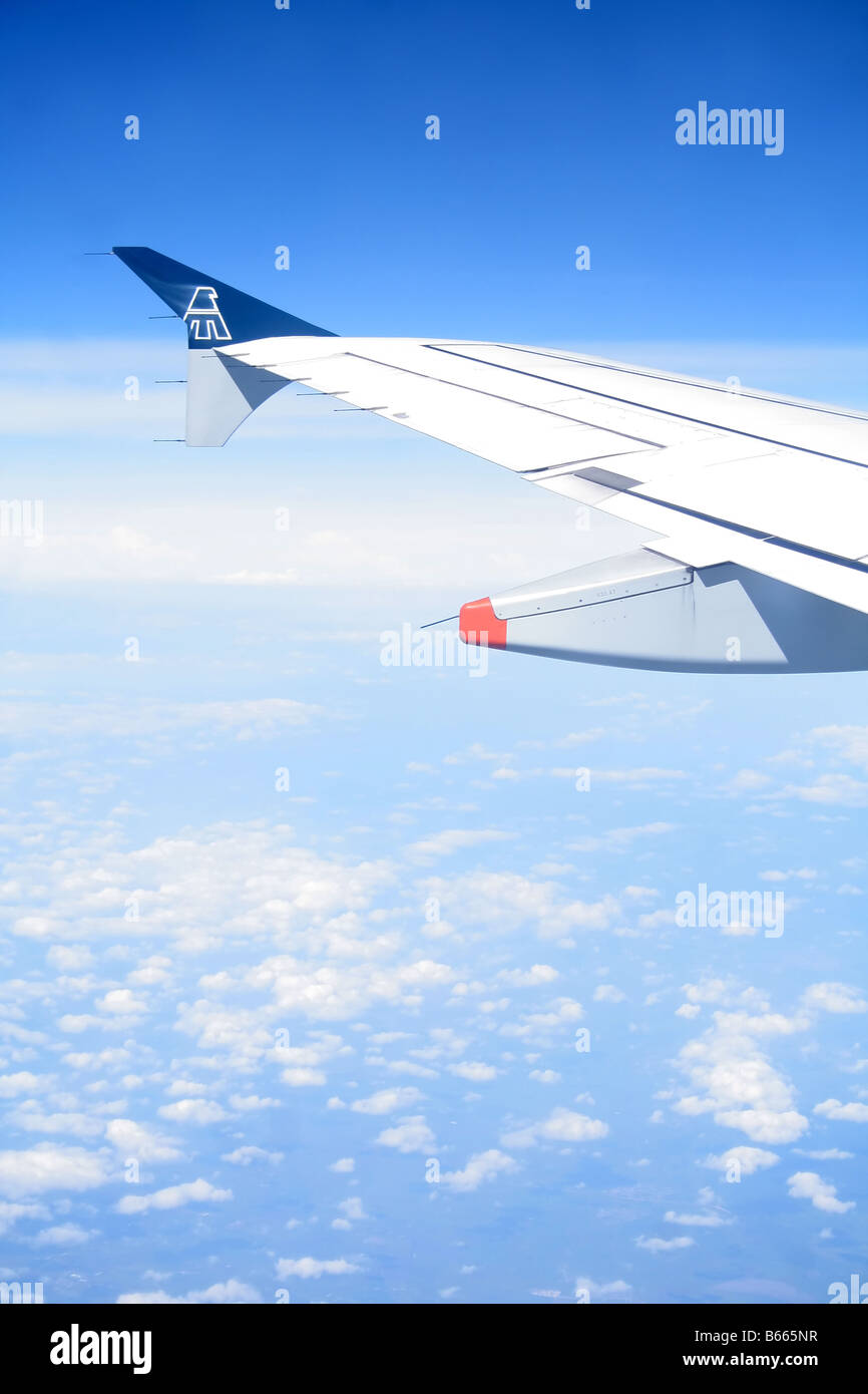 A airplane wing over a blue sky with some clouds Stock Photo - Alamy