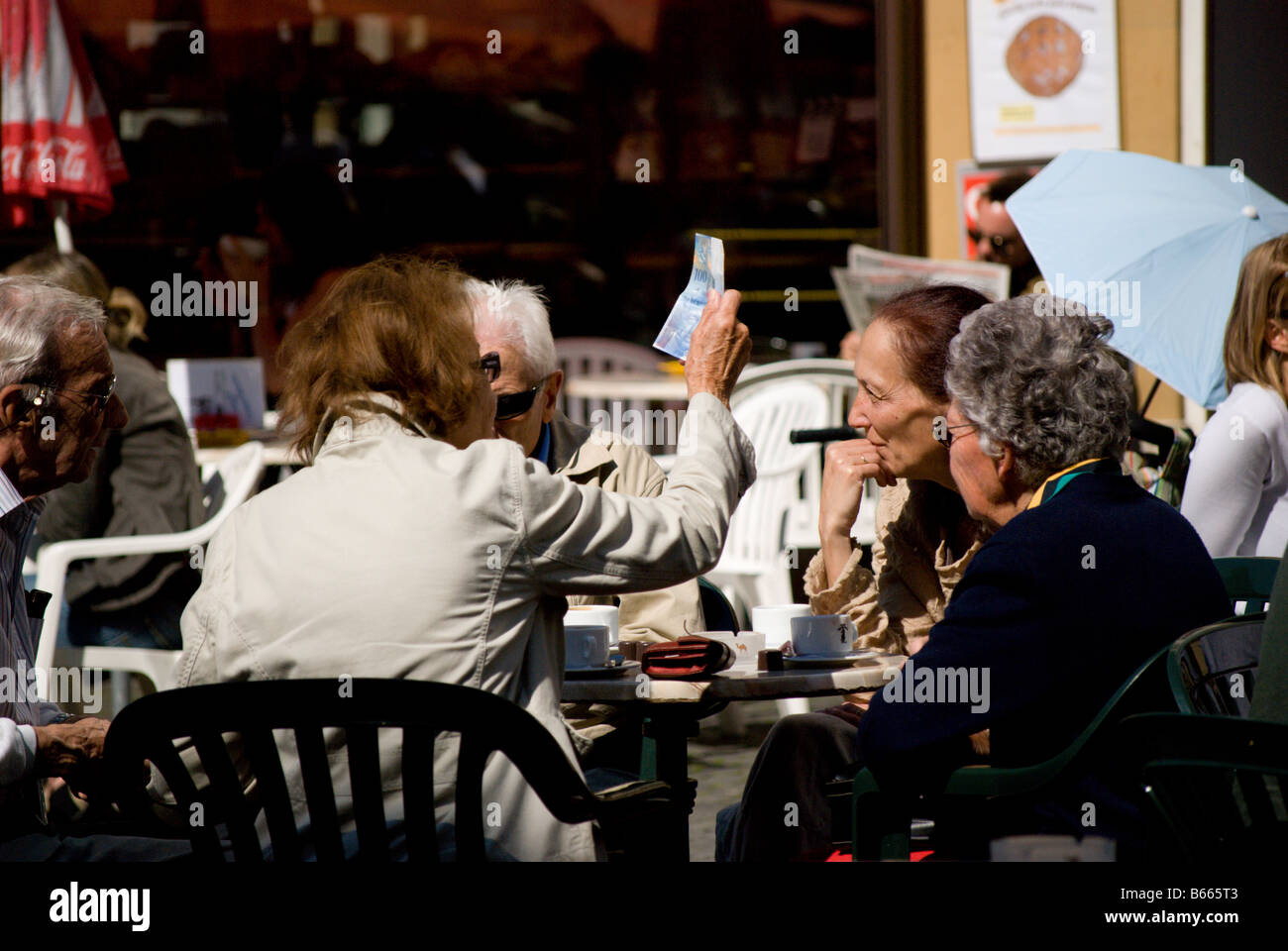 A group of older people sit at an open air cafe and have coffee Stock Photo