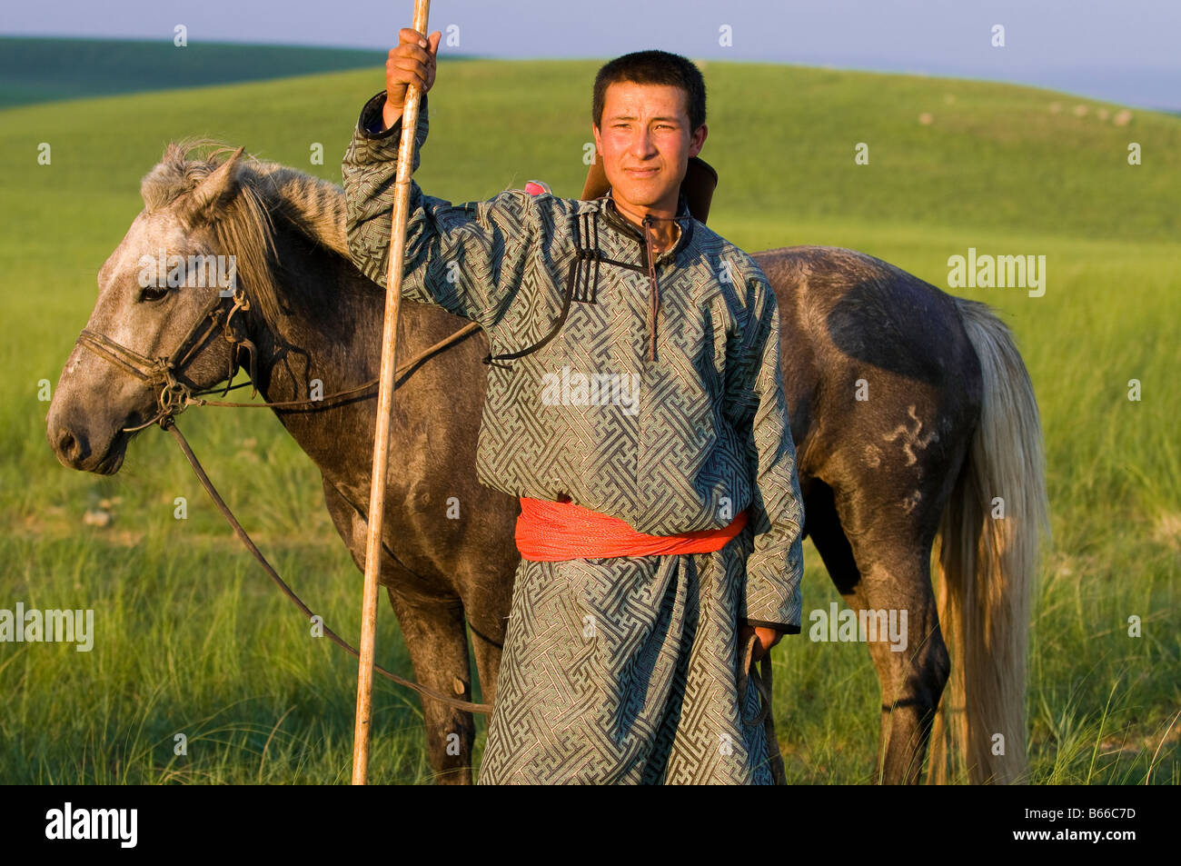 Grasslands herdsman on horseback catches horse with rope and pole urga ...