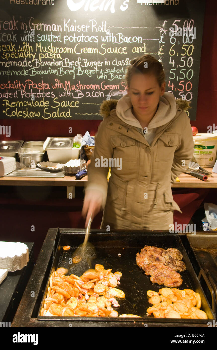Cooking pork steaks on a food stall at the German Christmas market held in Kingston upon Thames Surrey England Stock Photo