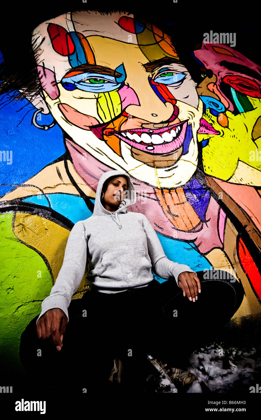 Black woman wearing a hoodie i front of a urban graffiti wall Stock Photo