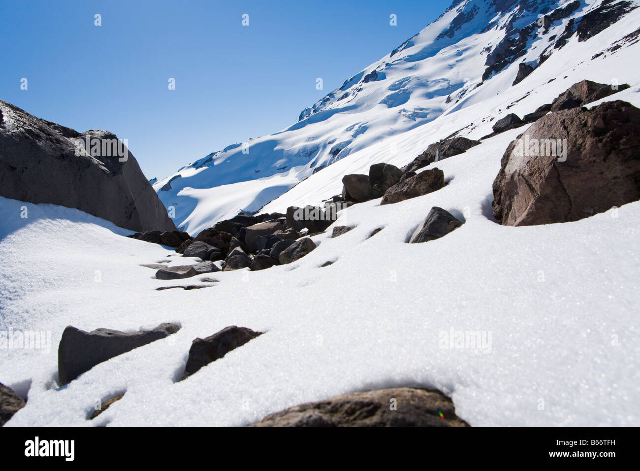 Melting snow revealing rocks on Mt Rainier Ski tracks in the distance