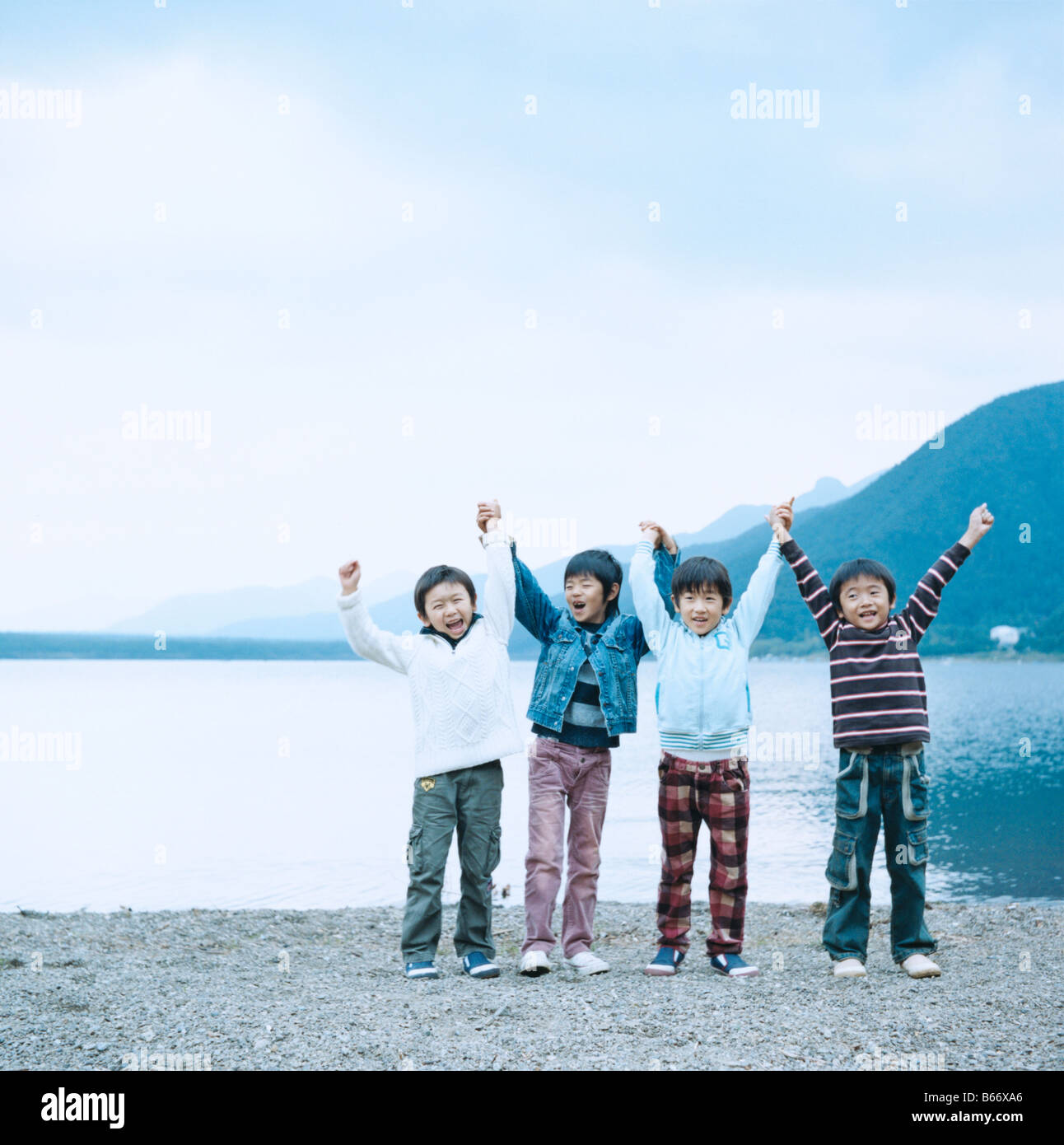 Four Boys Cheering at Lakeside Stock Photo