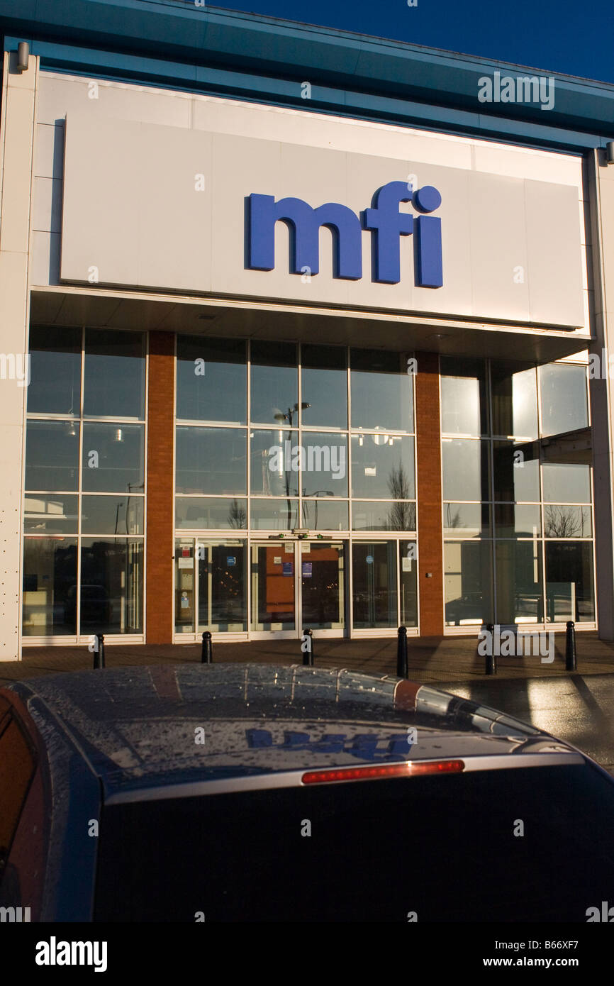 MFI store on retail park closed down & empty name is reflected in the roof of a car, broken by the line of the tailgate Stock Photo