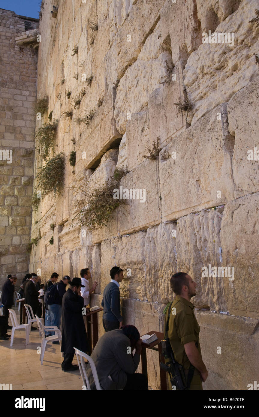 Israel Jerusalem Old City Western Wall young man in white kissing the wall in reverence with notes in cracks Stock Photo