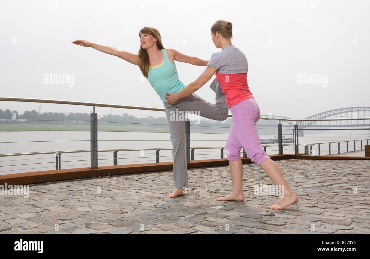 A personal trainer helping a woman practise yoga Stock Photo - Alamy