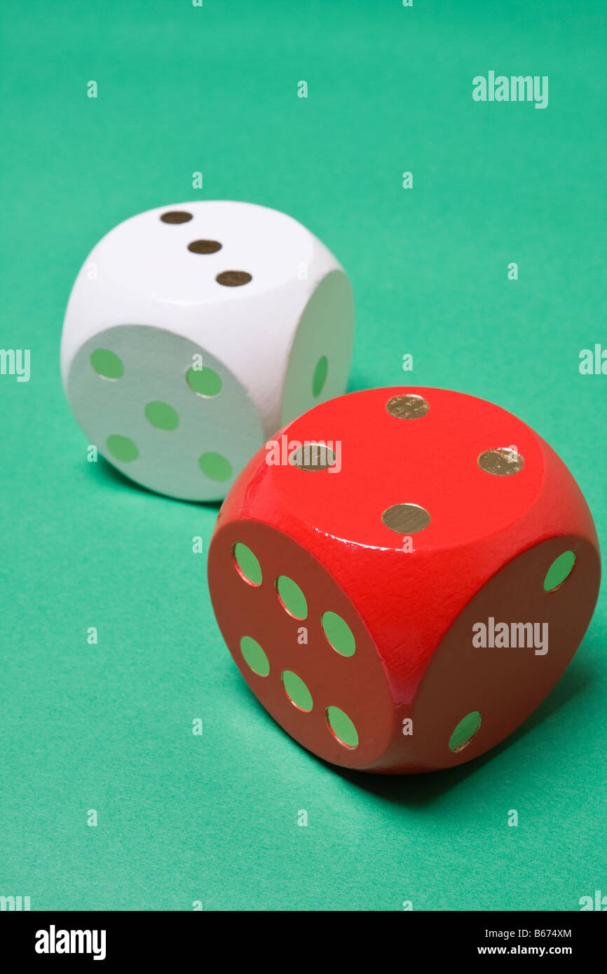 Red and white dice on green background showing three and four, total seven Stock Photo