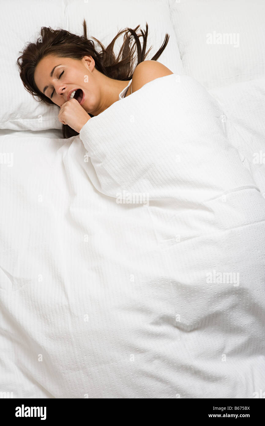 Woman yawning in bed Stock Photo