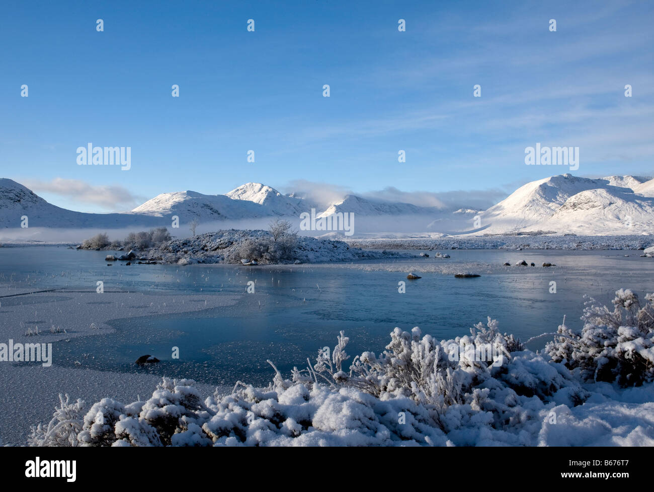 Beautiful morning scene across Rannoch Moor highlighting the early morning mist, the frozen loch, and stunning snow on mountains Stock Photo