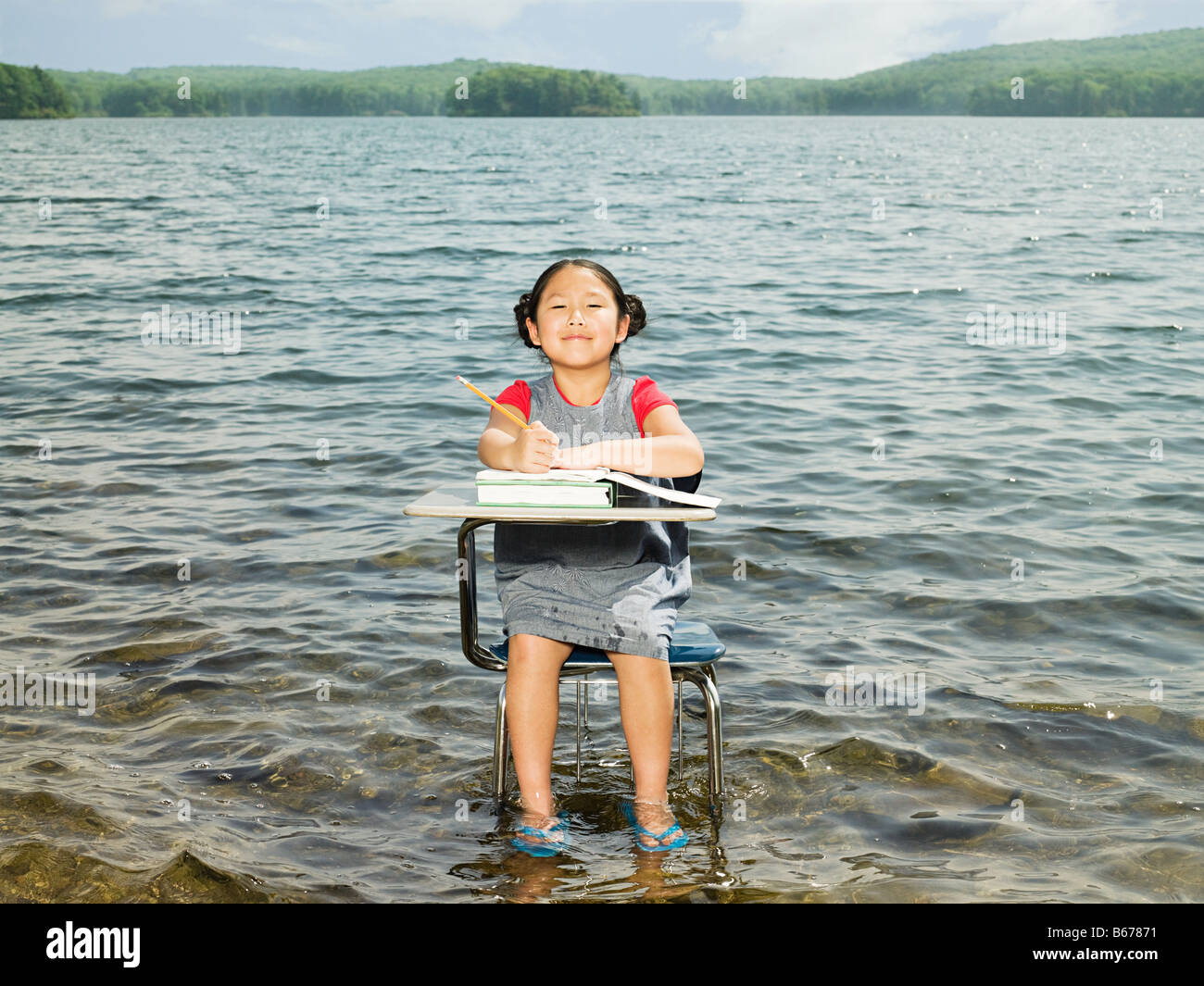 A girl sat at a desk in a lake Stock Photo