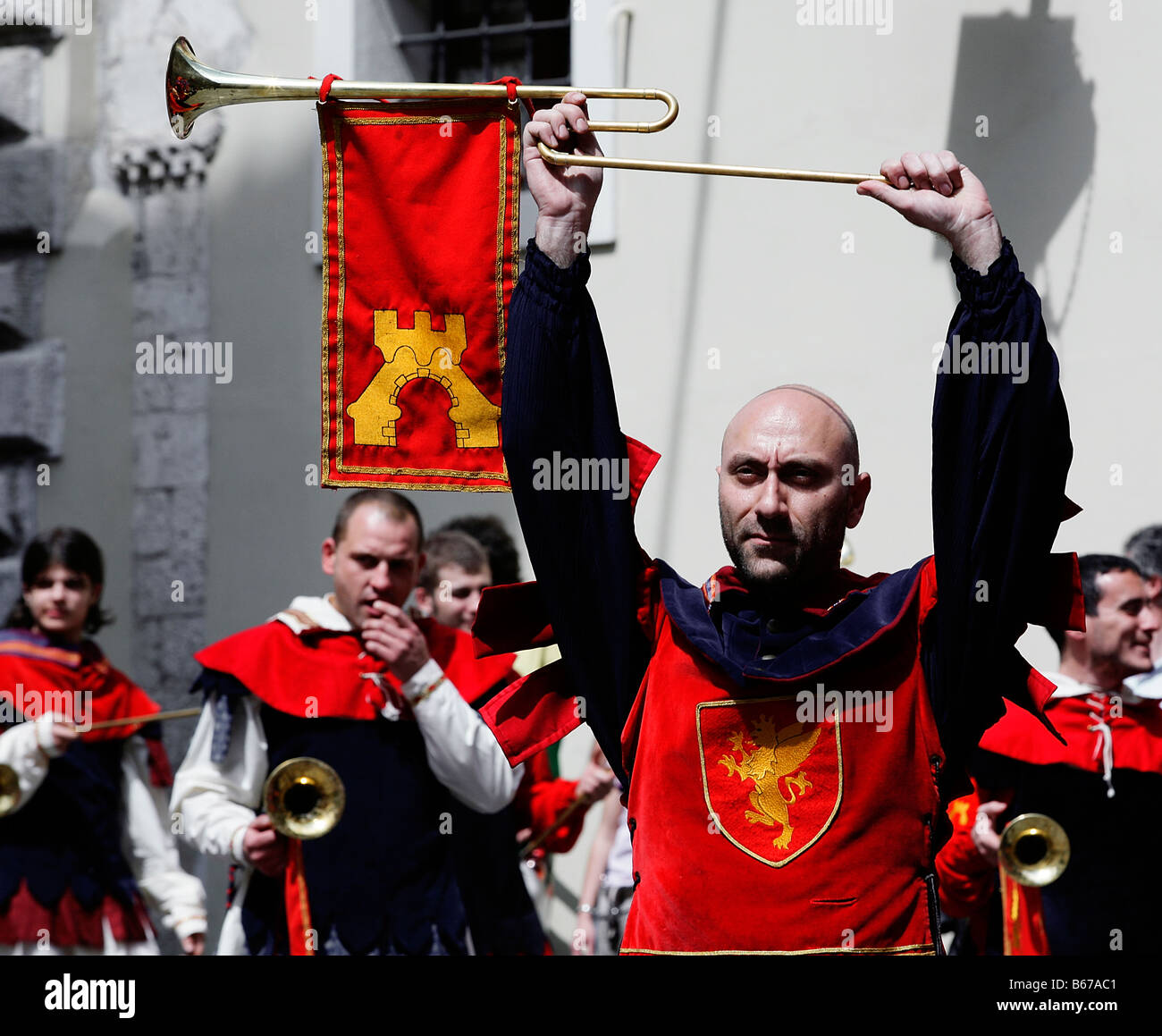 man marching in mediaeval costume holds trumpet above head in reenactment event Corsa all'Anello in Narni, Umbria, Italy Stock Photo