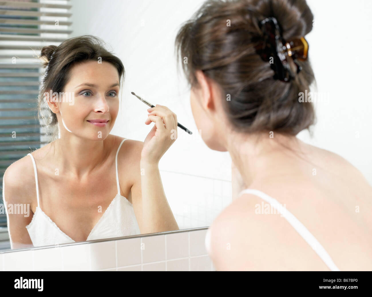 Woman in bathroom, applying makeup Stock Photo Alamy