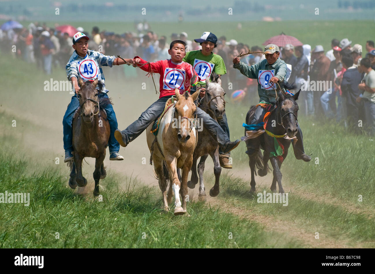 Ethnic Mongolian costumed boy jockeys race horses at summertime Naadam Festival Xiwuzhumuqinqi Inner Mongolia China Stock Photo