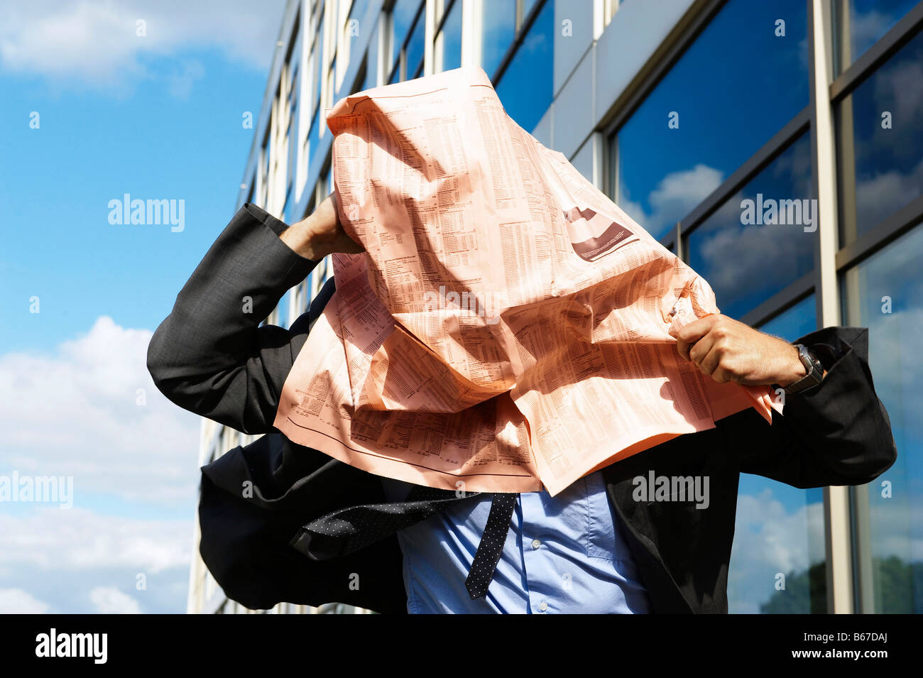 Businessman with newspaper over face Stock Photo