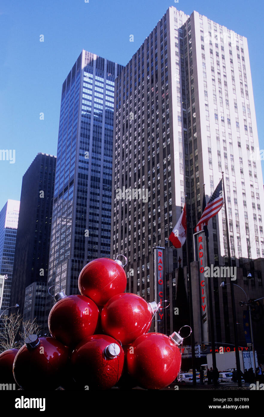 Skyscrapers on Sixth Avenue, (Avenue of the Americas) New York City. Radio City Music Hall. Giant red Christmas decorations on the street. USA Stock Photo