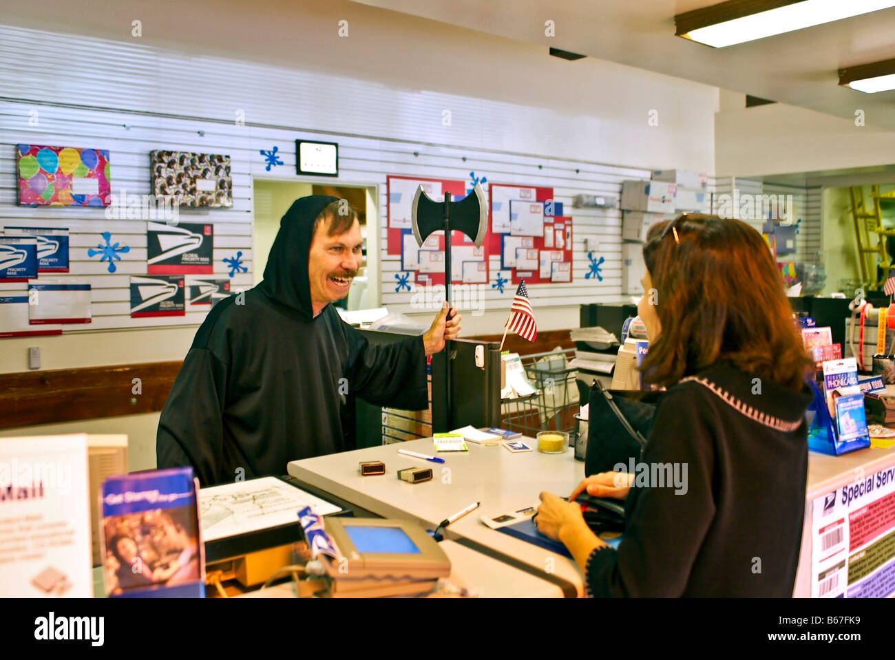 US Postal Service clerk waving toy ax and amusing customer day before Halloween in Laguna Niguel, CA Stock Photo