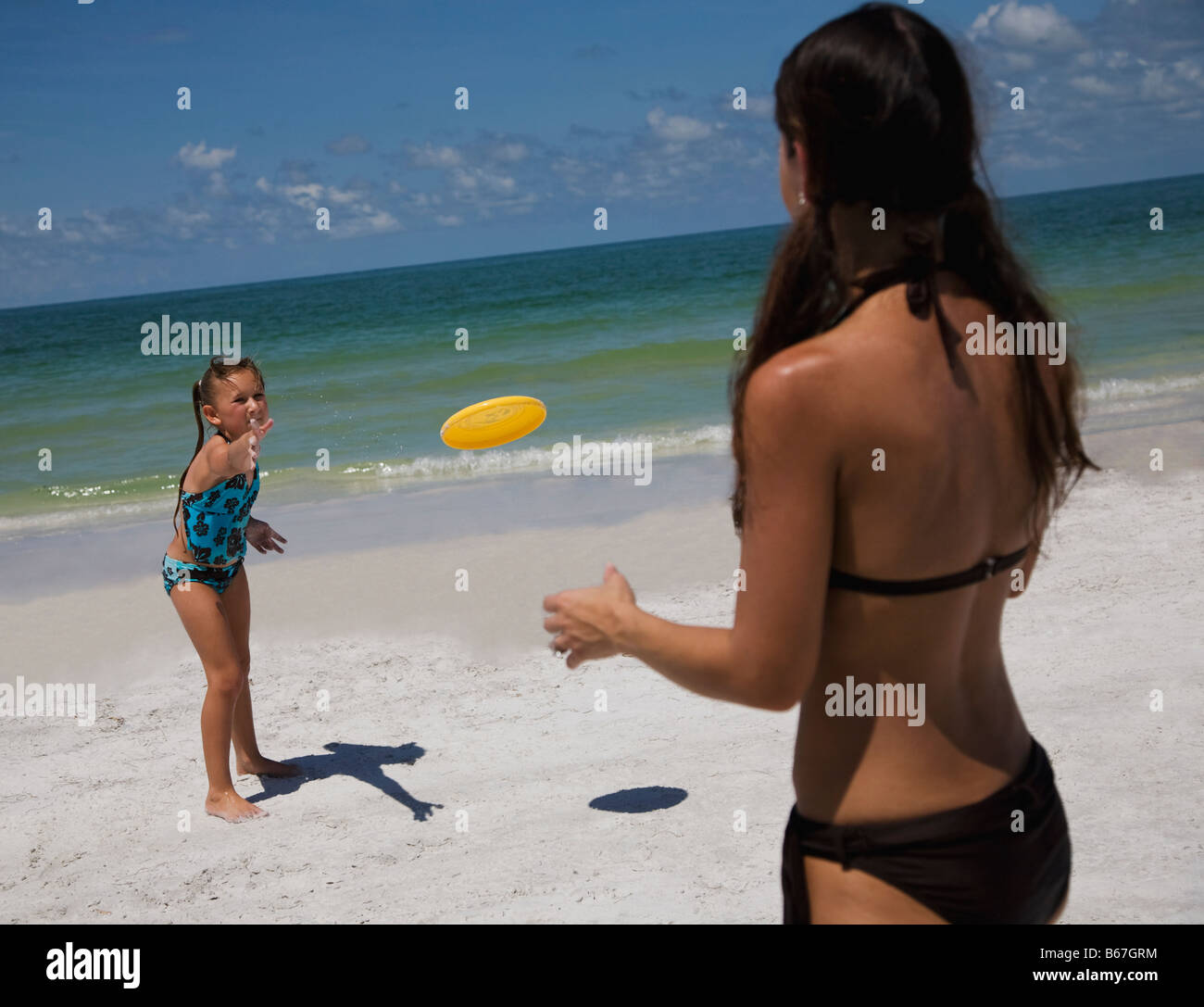 Mother and daughter (5-9) playing frisbee on beach Stock Photo