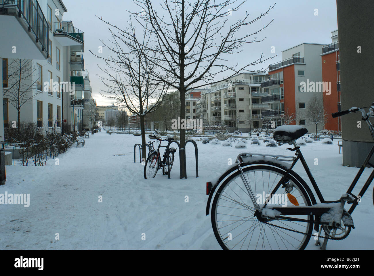 Bicycles parked along a snow covered street in the Hammarby sjöstad district of Stockholm in Sweden Stock Photo