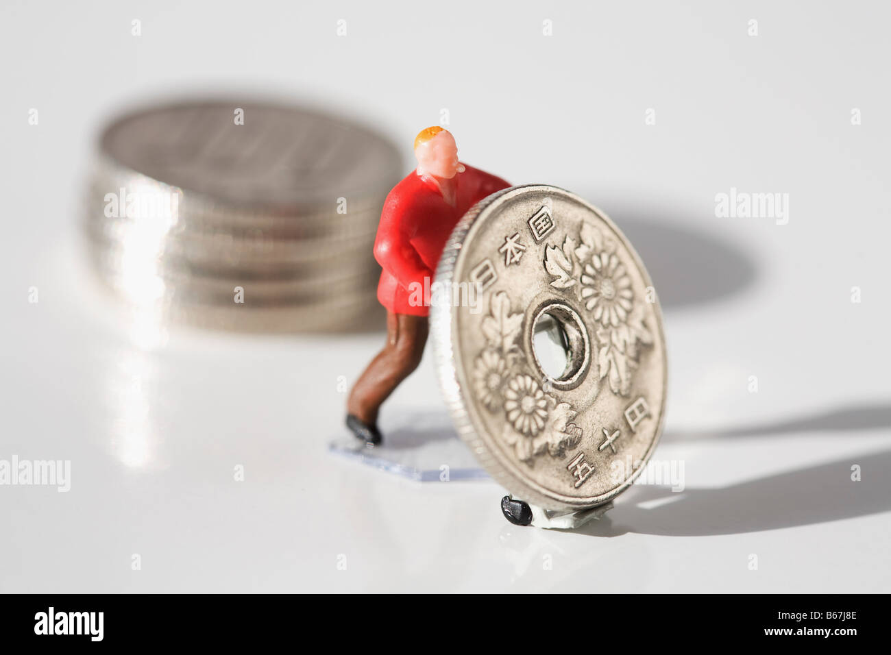 Figurine of a manual worker pushing a Chinese coin Stock Photo