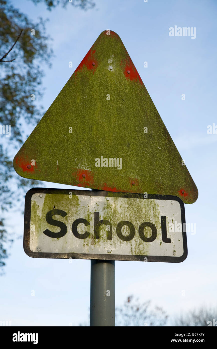 Triangle / triangular hazard sign warning for school children the road, obscured by moss or algae growing on its surface. Stock Photo