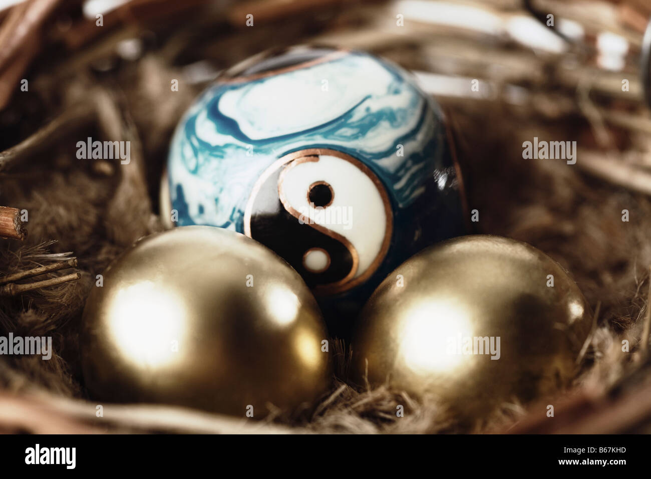 Close-up of golden eggs with a yin yang ball in a bird's nest Stock Photo