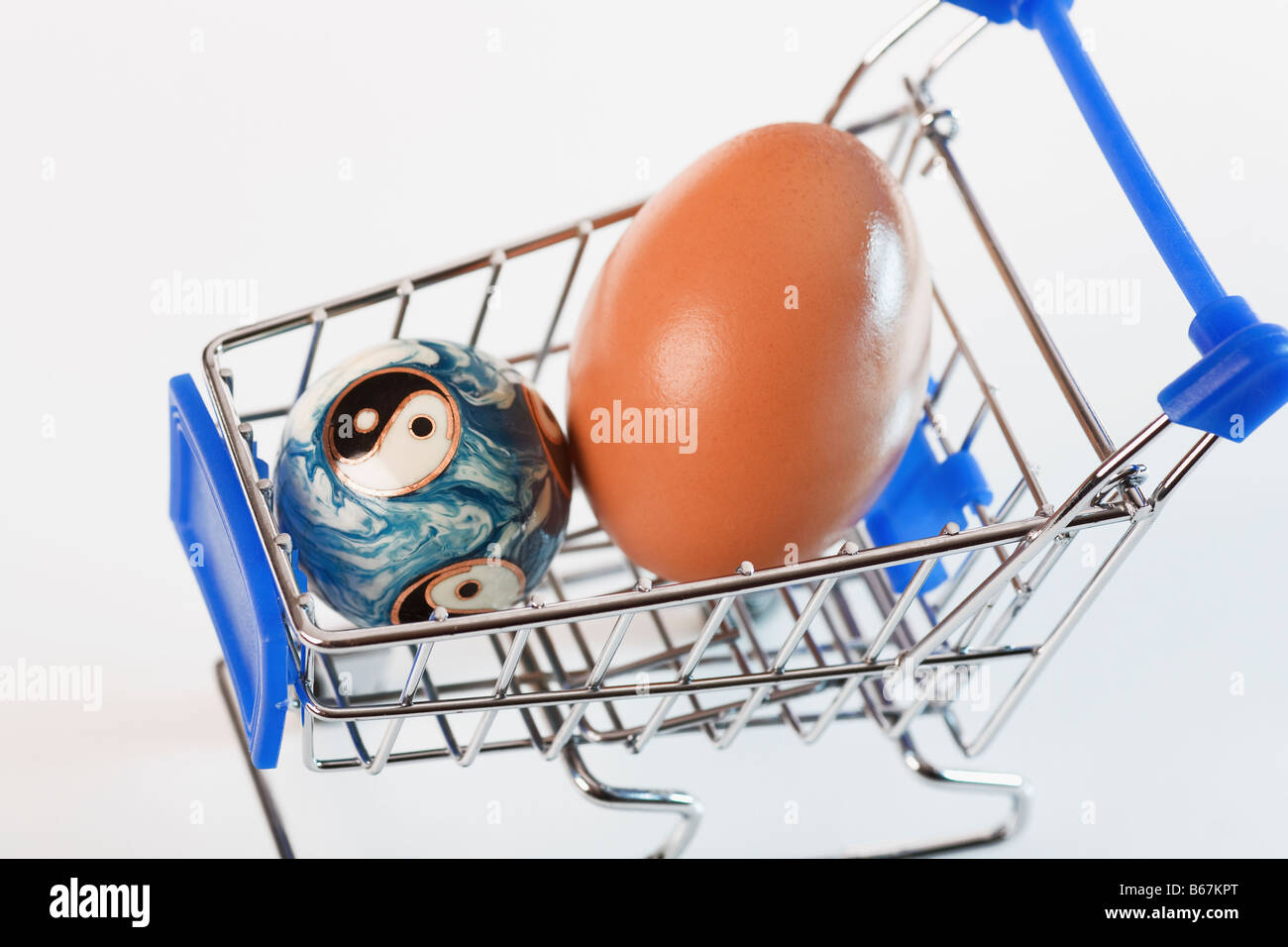 Close-up of a brown egg and a yin yang ball in a shopping cart Stock Photo
