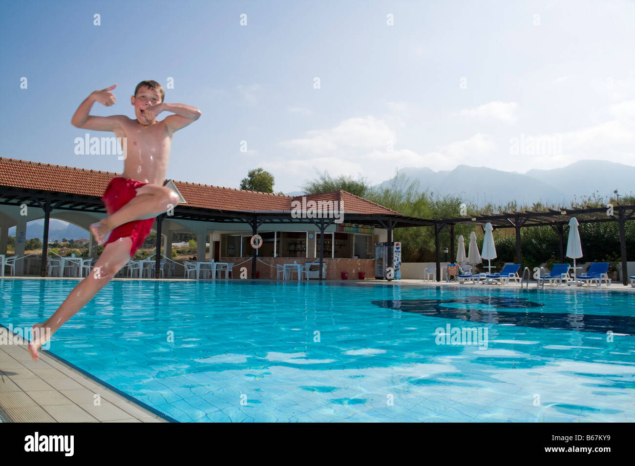 Boy in mid air jumping in swimming pool Stock Photo