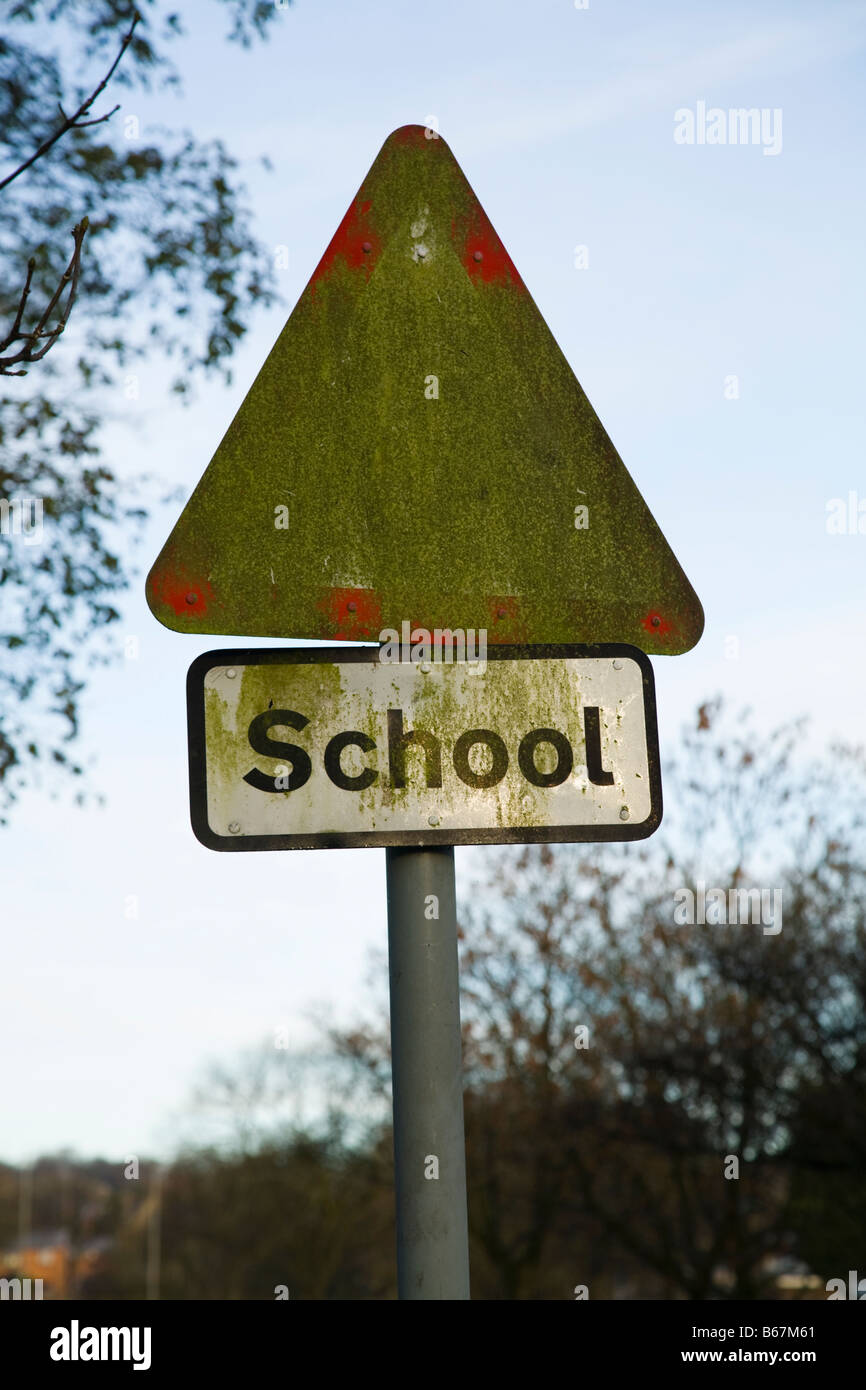 A hazard sign warning for school children the road which is obscured by moss or algae growing on its surface. Stock Photo