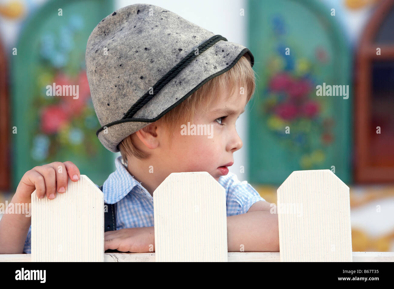 Boy (3-4 years) standing behind a fence Stock Photo